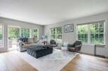 Step into this inviting living room, bathed in natural light from large windows overlooking lush greenery.