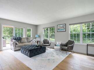 Step into this inviting living room, bathed in natural light from large windows overlooking lush greenery.