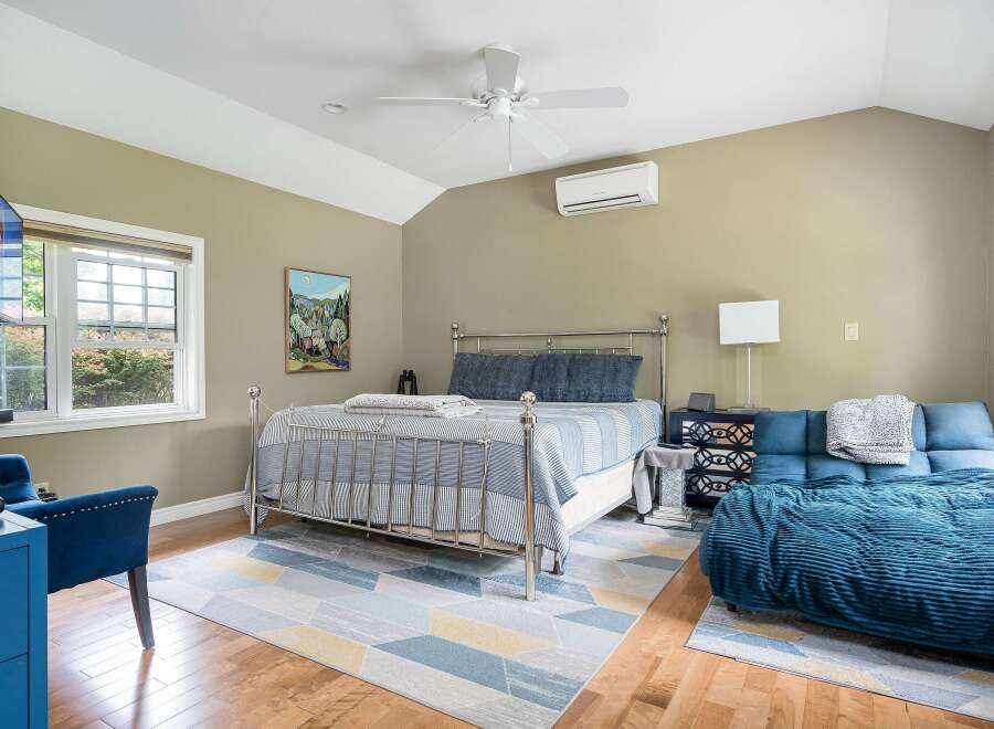 Experience comfort and style in this inviting bedroom, featuring a sleek metal-frame bed adorned with blue striped bedding and plush pillows.