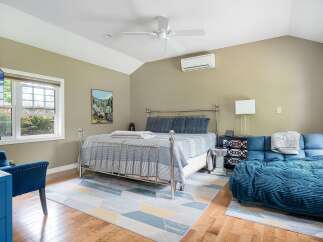 Experience comfort and style in this inviting bedroom, featuring a sleek metal-frame bed adorned with blue striped bedding and plush pillows.