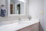 This modern bathroom features a sleek white vanity with a marble countertop and a chrome faucet.