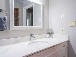 This modern bathroom features a sleek white vanity with a marble countertop and a chrome faucet.