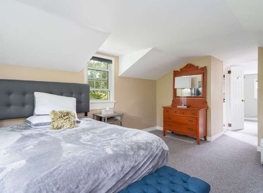Discover comfort and style in this charming bedroom, featuring a plush grey tufted headboard and a soft, textured grey blanket.