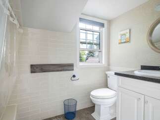 This bright and airy bathroom features a clean white subway tile shower surround and a modern vanity with a dark granite countertop.