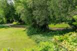 Experience serene living with this picturesque property featuring a lush green lawn leading to a tranquil stream.