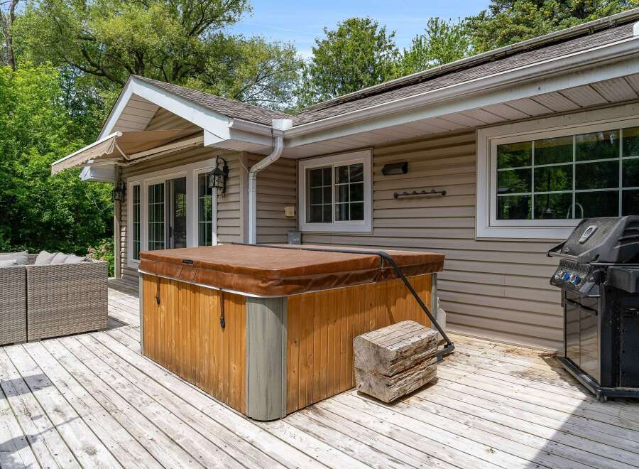 Enjoy outdoor living at its finest with this spacious deck featuring a relaxing hot tub and a convenient grill, perfect for entertaining.