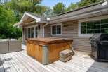 Enjoy outdoor living at its finest with this spacious deck featuring a relaxing hot tub and a convenient grill, perfect for entertaining.