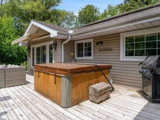 Enjoy outdoor living at its finest with this spacious deck featuring a relaxing hot tub and a convenient grill, perfect for entertaining.