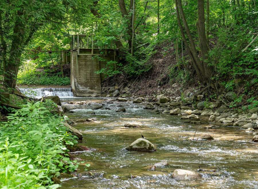Discover a serene natural retreat with this charming property, featuring a picturesque stream flowing through lush greenery.