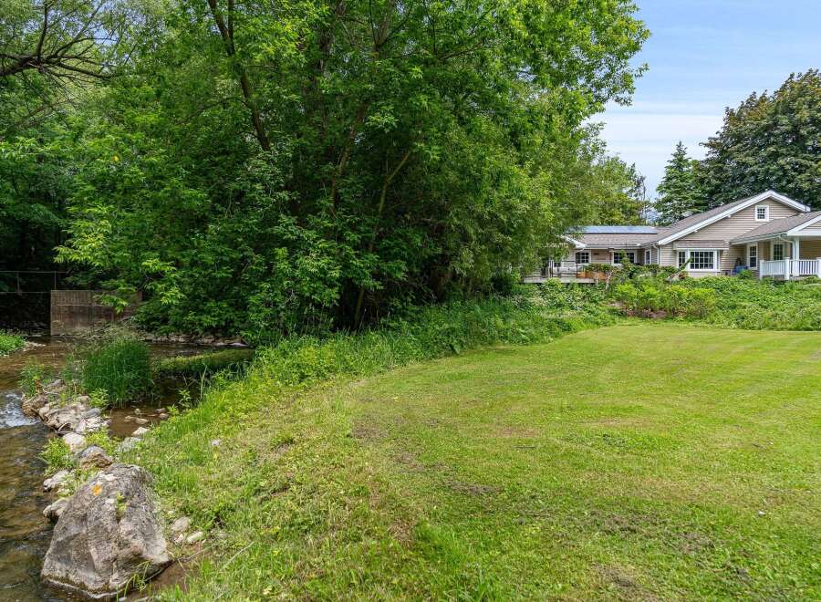 Enjoy serene living with this charming home featuring a beautiful creek and lush greenery.