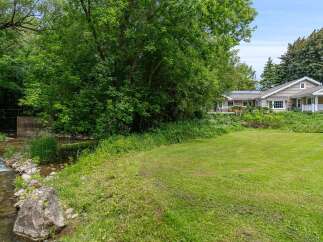 Enjoy serene living with this charming home featuring a beautiful creek and lush greenery.
