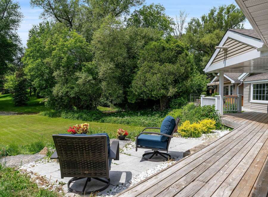 Enjoy outdoor living with this charming patio featuring comfortable seating and vibrant floral arrangements.
