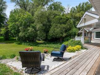 Enjoy outdoor living with this charming patio featuring comfortable seating and vibrant floral arrangements.