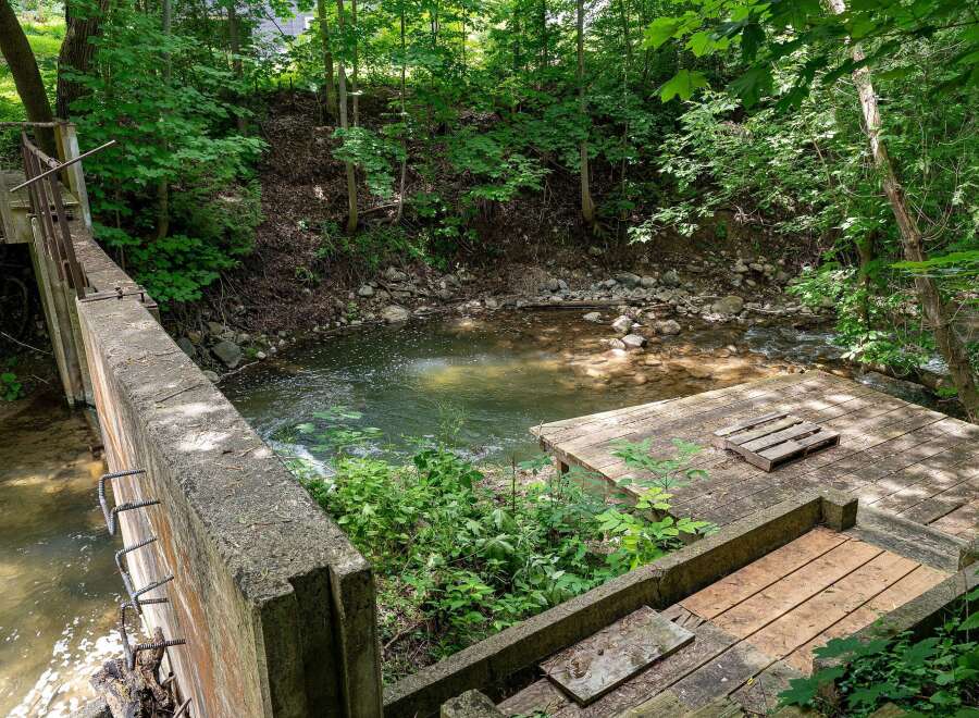 Discover a unique property featuring a charming creek running alongside a concrete structure, perfect for outdoor enthusiasts.
