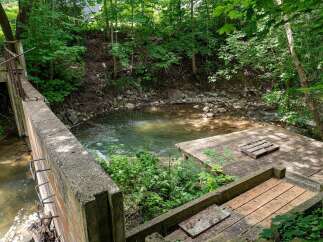 Discover a unique property featuring a charming creek running alongside a concrete structure, perfect for outdoor enthusiasts.