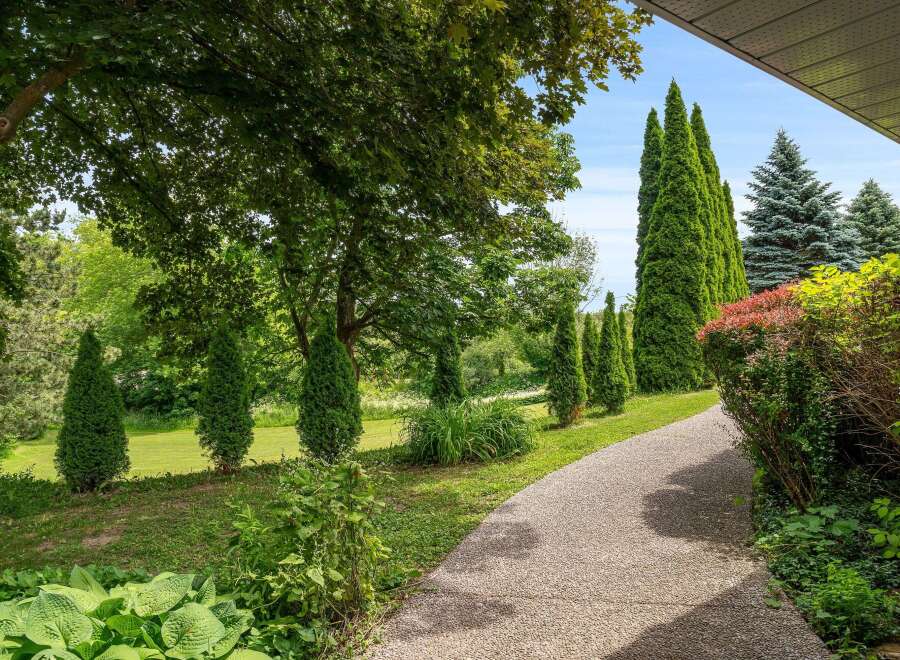 Discover a beautifully landscaped property featuring a charming gravel pathway winding through lush greenery.