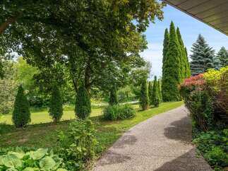 Discover a beautifully landscaped property featuring a charming gravel pathway winding through lush greenery.