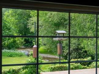 Enjoy serene living with this picturesque view of a flowing creek and lush greenery right from your window.