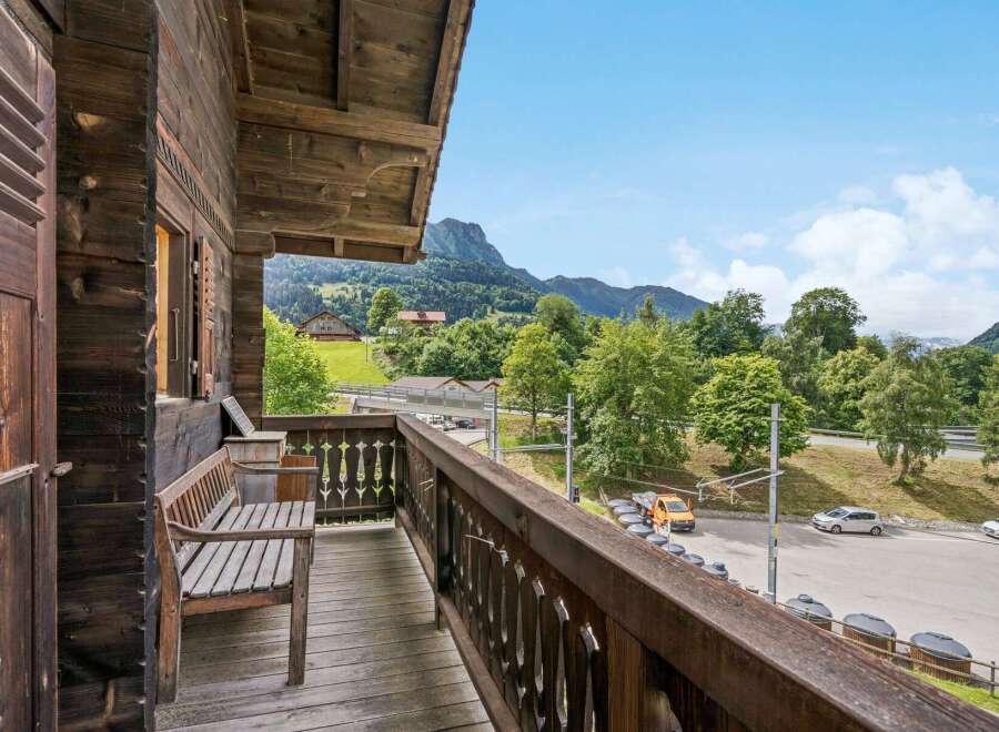 Enjoy breathtaking mountain views from this charming wooden balcony, complete with a rustic bench perfect for relaxing.