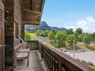 Enjoy breathtaking mountain views from this charming wooden balcony, complete with a rustic bench perfect for relaxing.