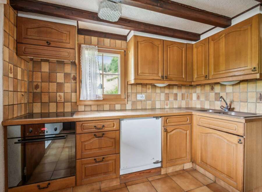 This charming kitchen features warm wooden cabinetry and a classic tiled backsplash, creating a cozy and inviting atmosphere.
