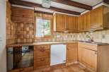 This charming kitchen features warm wooden cabinetry and a classic tiled backsplash, creating a cozy and inviting atmosphere.