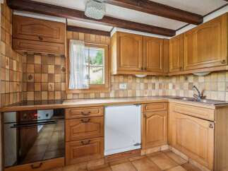 This charming kitchen features warm wooden cabinetry and a classic tiled backsplash, creating a cozy and inviting atmosphere.