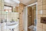 This charming bathroom features a classic tiled design with a functional shower-tub combination and a convenient vanity with a mirror.