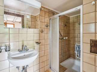 This charming bathroom features a classic tiled design with a functional shower-tub combination and a convenient vanity with a mirror.