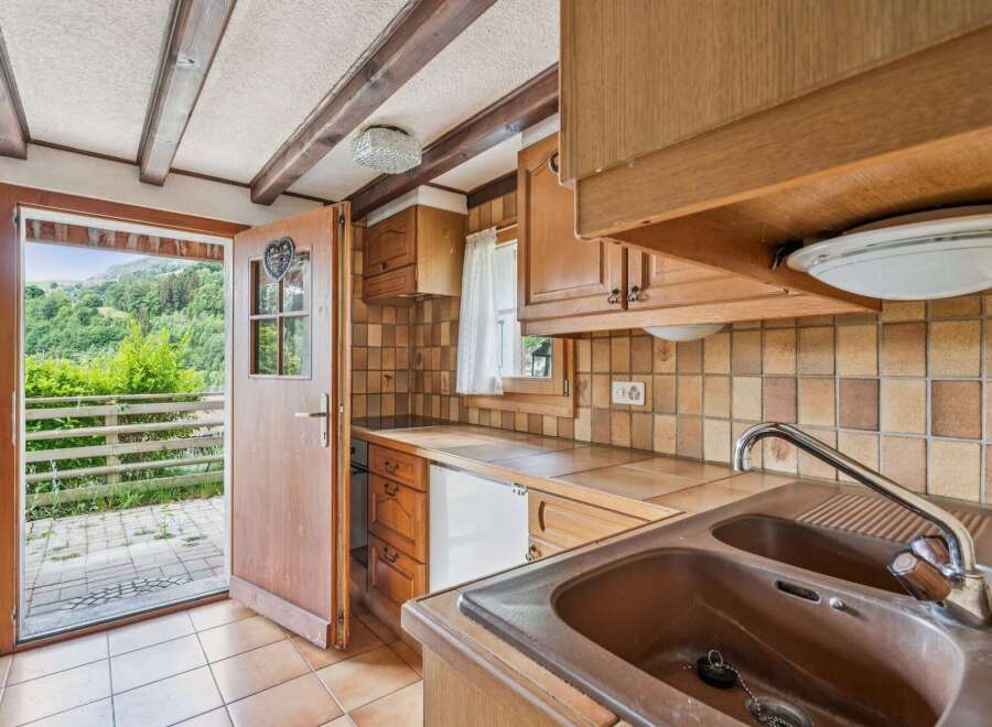 Step into this charming kitchen featuring rustic wooden cabinetry and warm-toned tiled backsplash.