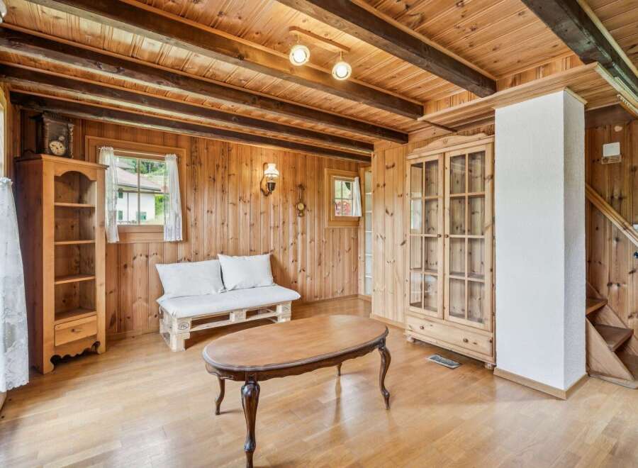 Step into this charming rustic living room, featuring warm wooden paneling and exposed beams for a cozy alpine feel.