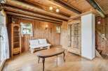 Step into this charming rustic living room, featuring warm wooden paneling and exposed beams for a cozy alpine feel.