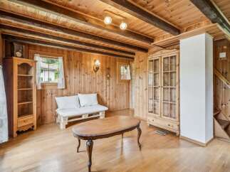 Step into this charming rustic living room, featuring warm wooden paneling and exposed beams for a cozy alpine feel.