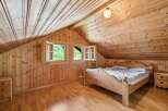 Experience rustic charm in this cozy attic bedroom, featuring warm wooden paneling throughout the walls and ceiling.