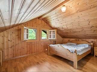 Experience rustic charm in this cozy attic bedroom, featuring warm wooden paneling throughout the walls and ceiling.