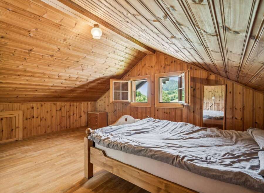 Experience rustic charm in this attic bedroom, featuring warm wooden paneling throughout the walls and ceiling.