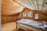 Experience rustic charm in this attic bedroom, featuring warm wooden paneling throughout the walls and ceiling.
