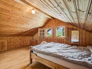 Experience rustic charm in this attic bedroom, featuring warm wooden paneling throughout the walls and ceiling.