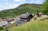 Experience sustainable living in this charming alpine home, featuring a prominent solar panel installation on its roof, perfect for eco-conscious buyers.