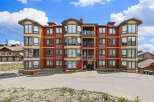 Experience luxury mountain living in this stunning condo complex, featuring a vibrant red and tan exterior with expansive windows offering breathtaking views.