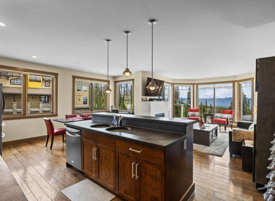 Experience breathtaking mountain views from this stunning condo, featuring a modern kitchen island with a double sink and ample cabinet space.