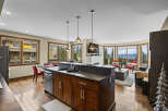 Experience breathtaking mountain views from this stunning condo, featuring a modern kitchen island with a double sink and ample cabinet space.