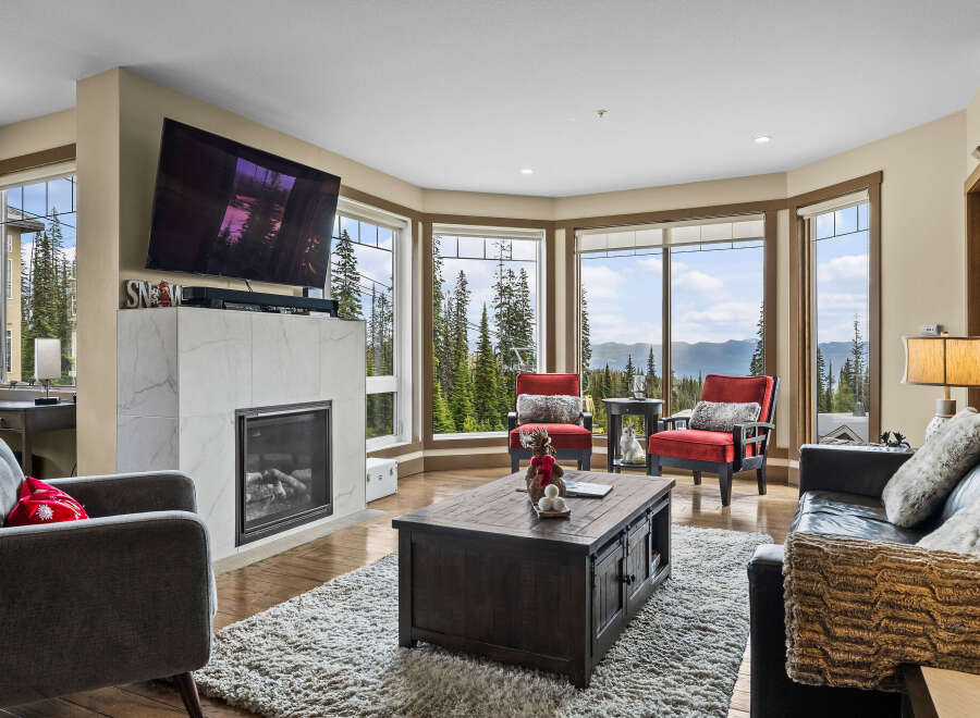 Experience breathtaking mountain views from this stunning living room, featuring a modern fireplace and expansive windows.
