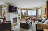 Experience breathtaking mountain views from this stunning living room, featuring a modern fireplace and expansive windows.