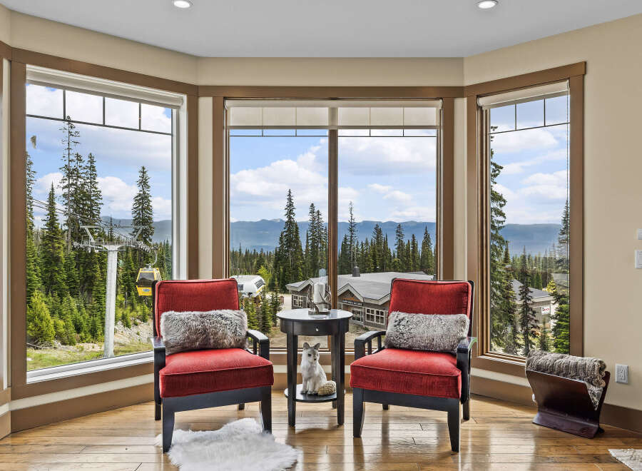Experience breathtaking mountain views from this stunning living area, featuring two plush red armchairs perfect for enjoying the scenery.