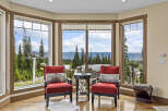 Experience breathtaking mountain views from this stunning living area, featuring two plush red armchairs perfect for enjoying the scenery.