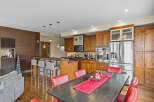 This spacious kitchen boasts rich wooden cabinetry, a large stainless steel refrigerator, and a breakfast bar with comfortable seating.