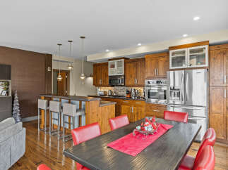 This spacious kitchen boasts rich wooden cabinetry, a large stainless steel refrigerator, and a breakfast bar with comfortable seating.