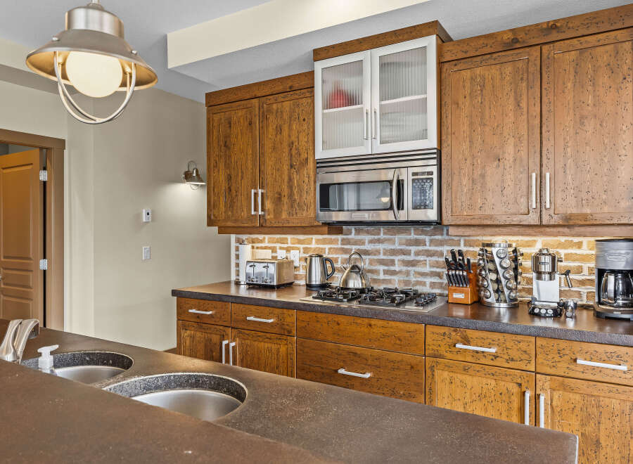 This kitchen boasts beautiful rustic wooden cabinetry complemented by a modern stainless steel microwave and gas stovetop.