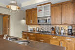 This kitchen boasts beautiful rustic wooden cabinetry complemented by a modern stainless steel microwave and gas stovetop.